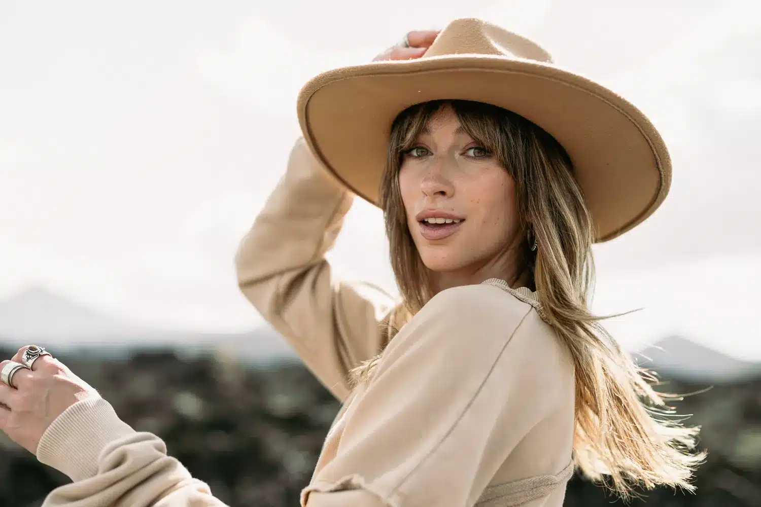 Portret van een vrouw met hoed in natuurlijk licht en open landschap
