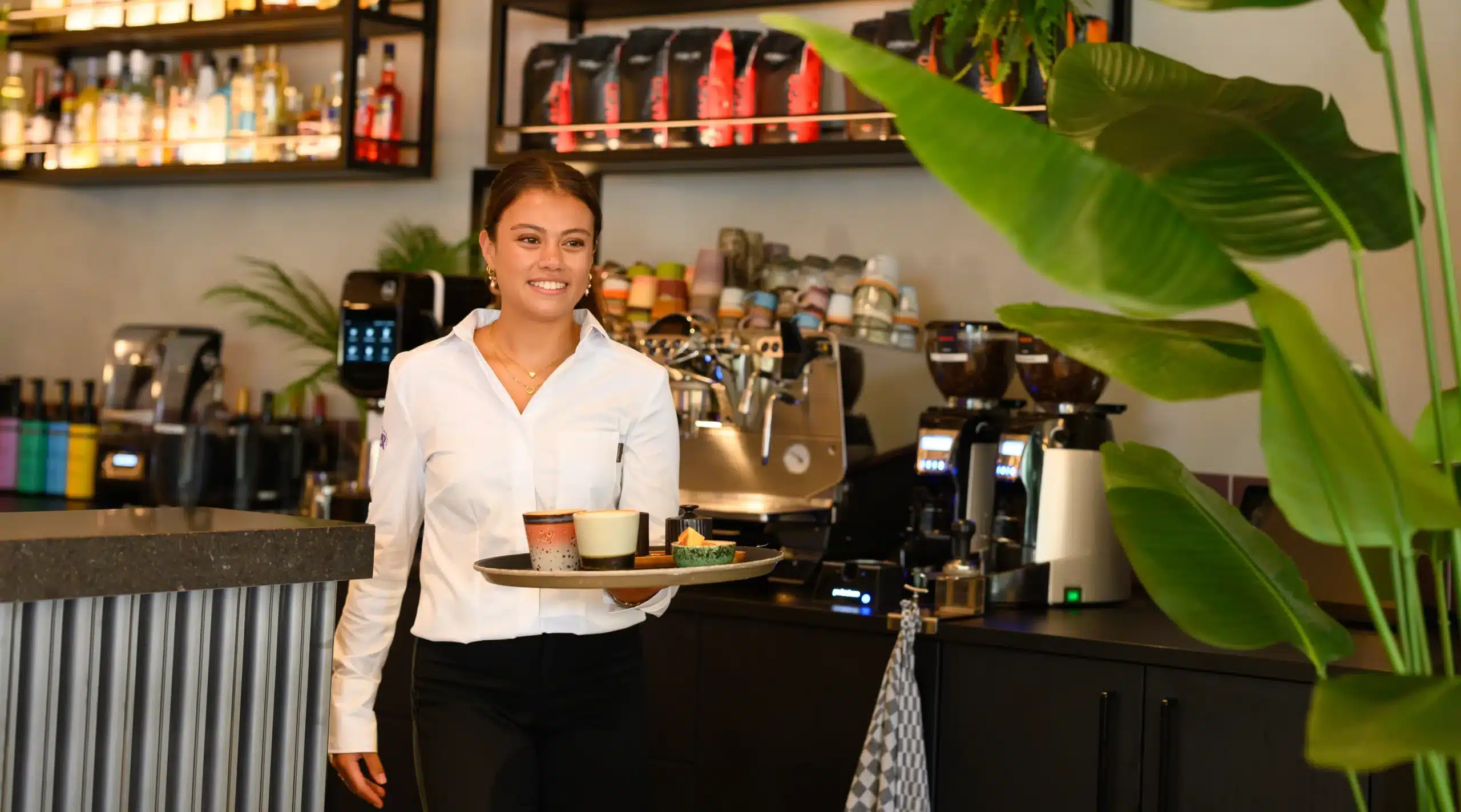 Medewerker van restaurant Fier serveert koffie in een sfeervol interieur