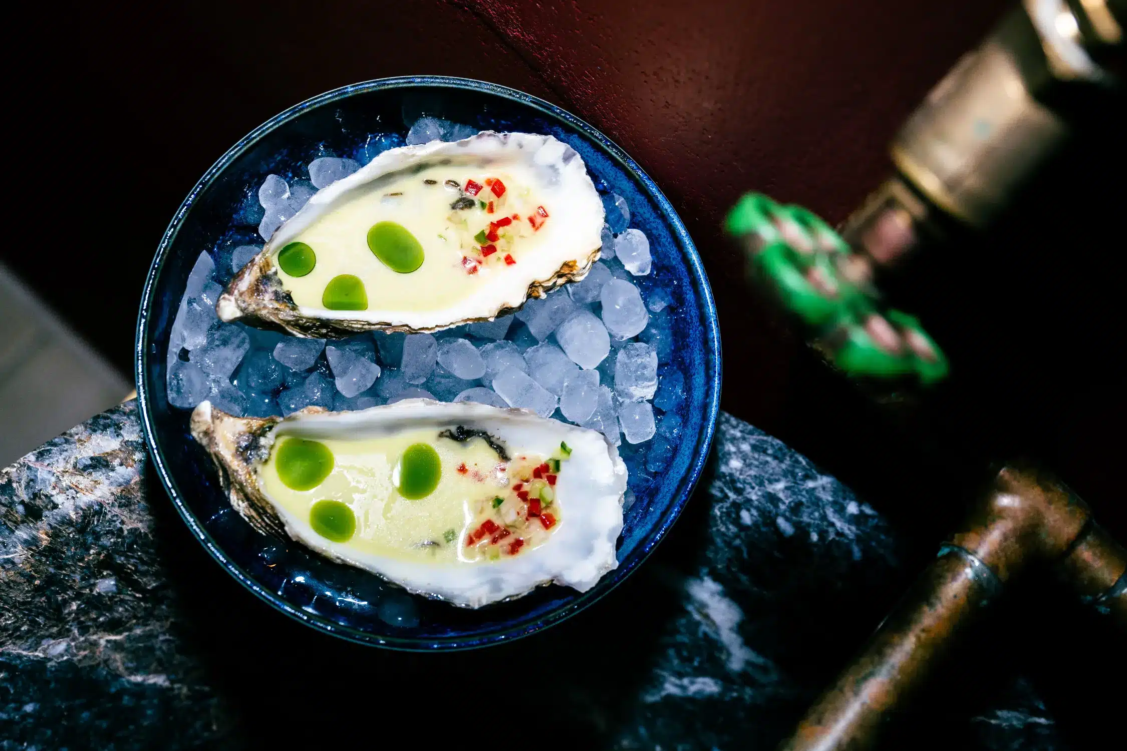 Culinaire foto van twee oesters op ijs in een donkerblauw bord