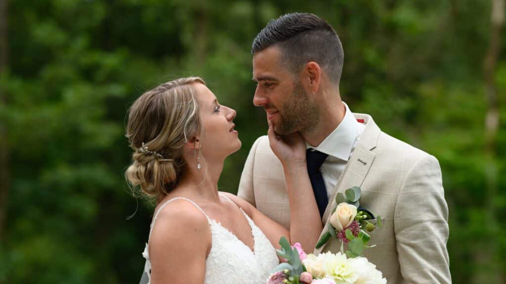 Bruid en bruidegom in liefdevol moment, gefotografeerd in een groene buitenlocatie