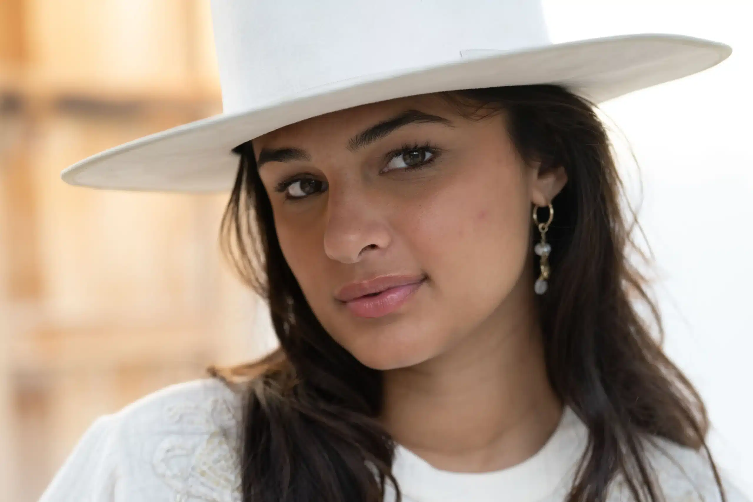 Portret van een jonge vrouw met witte hoed in zacht daglicht