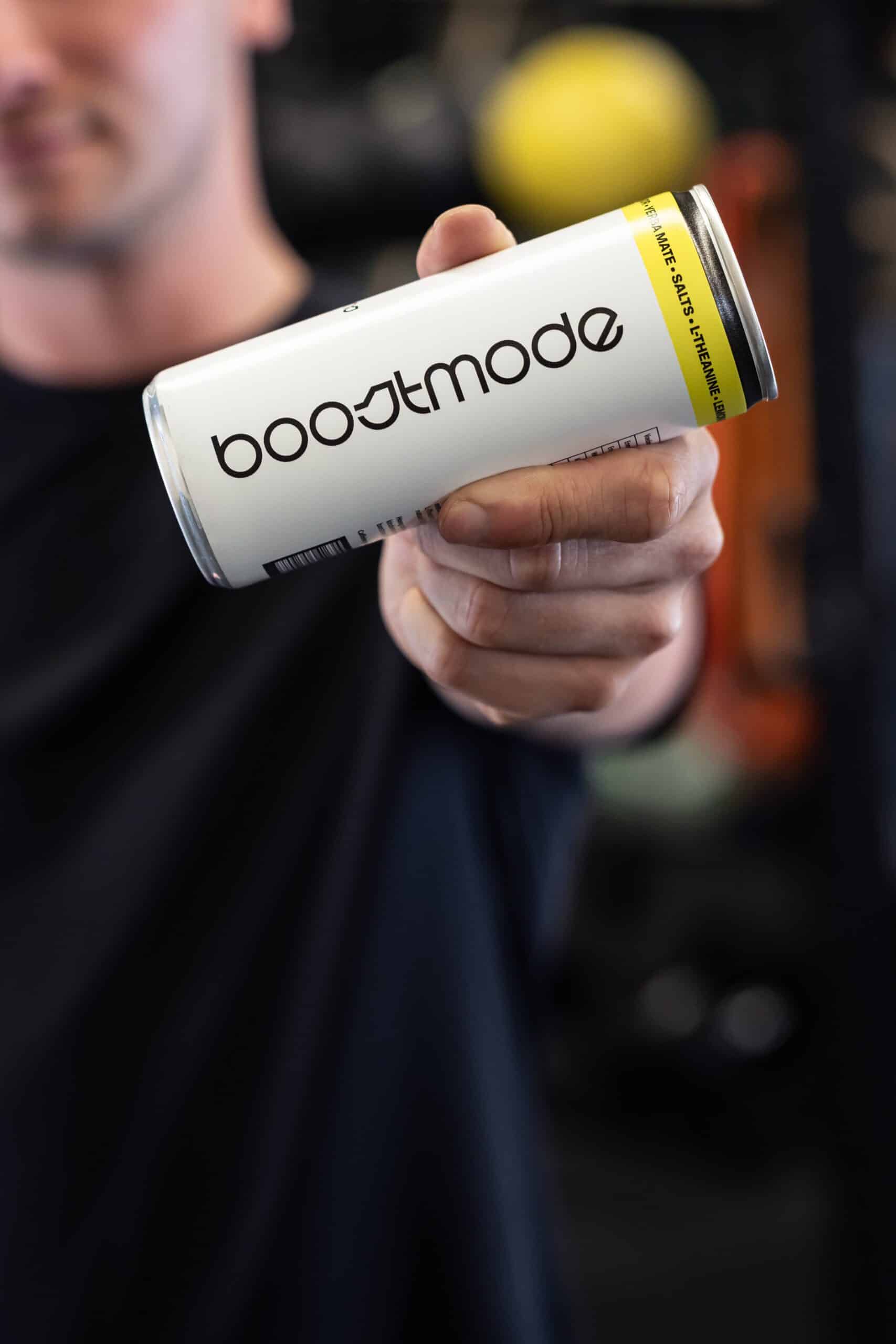 Hand toont Boostmode energy drink in fitnessomgeving, brandingbeeld door Diana Fotografie