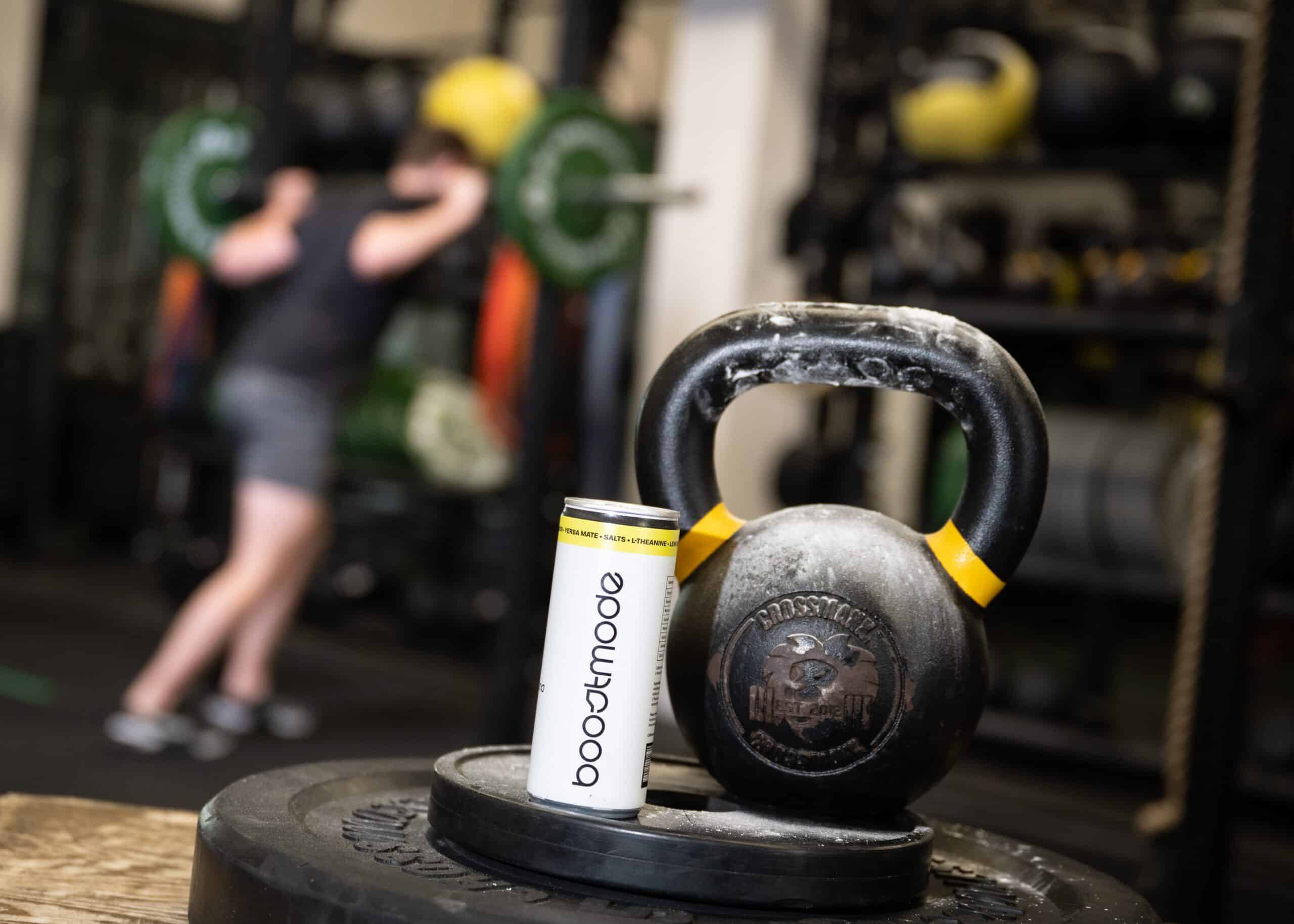 Boostmode en kettlebell op stapel gewichten, met sporter op de achtergrond