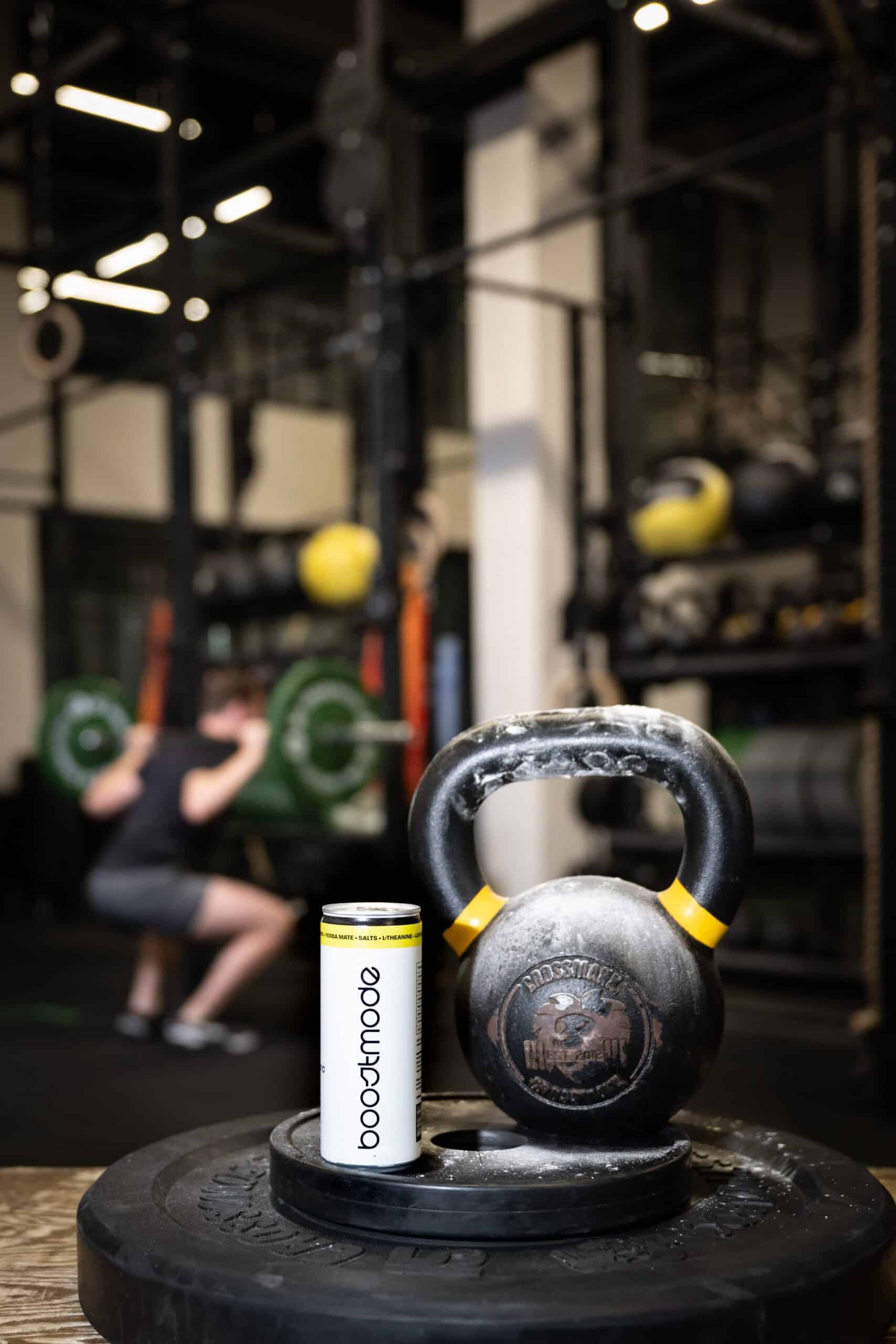 Boostmode energy drink met kettlebell op gymvloer, gefotografeerd door Diana Fotografie